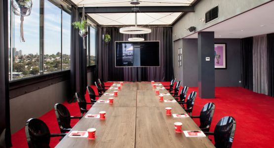 A room with a long conference table and red carpet